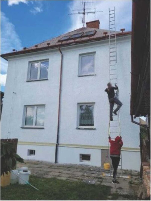 Handwerker auf einer Leiter bei Arbeiten an der Fassade