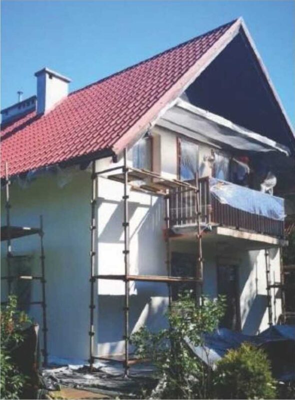 Giebelseite eines Hauses mit rotem Ziegeldach und Gerüst während der Beschichtung
